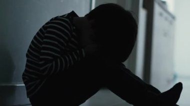 Fearful kid suffering from bullying and trauma sitting on floor covering face. Scared child remembering trauma