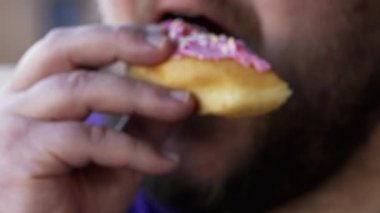Person eating unhealthy food. Close up hand holding donut. Guy takes a bite of carb food snack