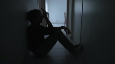 Yerde oturan bunalımlı bir adam. Alnını tutan mutsuz insan zihinsel hastalıktan muzdarip. Depresyon kavramı