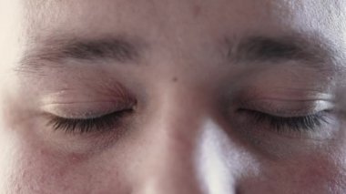 Person closing eyes in meditation and opening looking at camera. Macro close up of calm man eye in contemplation