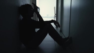 One anxious depressed man in despair sitting at home in the dark. Person suffering from mental illness alone in corridor feeling shame and regret