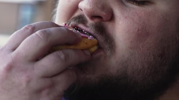 不健康な食べ物を食べてぽっちゃり男 ドーナツスナックを一口飲んでいる人 — ストック動画