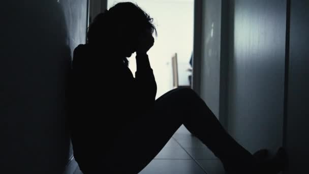 うつ病に苦しむ暗闇の中で家に座っている欲求不満女性のシルエット — ストック動画