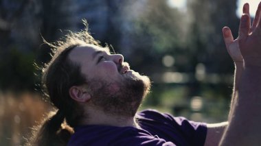 Religious young man raising arms in the air feeling the presence of God. Dramatic person raising hands into sky asking for help