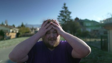 One desperate young fat man feeling upset. Overweight person feeling angry suffering from emotional problems walking outdoors. Tracking shot