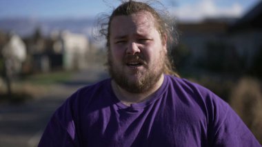 One anxious young man standing outdoors feeling distressed. An unhappy overweight guy suffering from mental regret