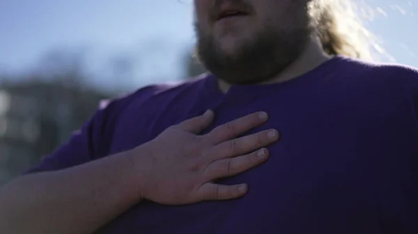 One overweight man with hand in chest having difficulty to breath. A fat person having heart pain
