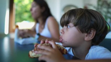 One pensive child eating bread. A thoughtful little boy eats food at morning breakfast table