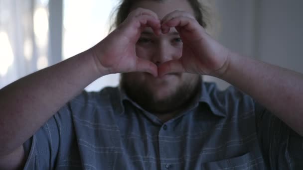 Ung Knubbig Man Gör Hjärtsymbol Med Händer Inomhus Lycklig Person — Stockvideo