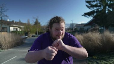 A fat relaxed man dances happily in the street. One funny overweight person dancing outdoors. Happiness laid back concept