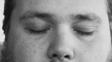 One young man smiling at camera in monochromatic black and white image. Macro eyes