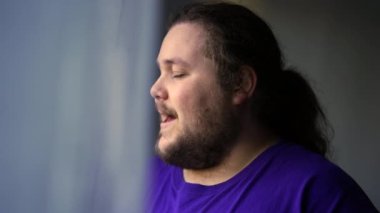 One happy casual chubby man smiling by home window looking out