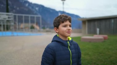 One happy young boy walking outside at city park during autumn season. Portrait face closeup of teenager kid strolling outdoors