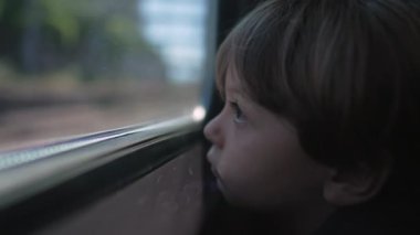 One sad little boy leaning on train window. Close up face of contemplative child. Thoughtful kid with serious expression