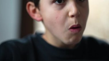 Young boy eating lunch. Portrait face closeup child eats food. Preteen seated at meal table
