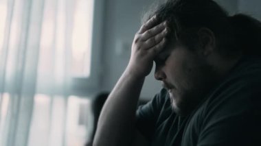 Depressed man sitting on couch. Sad unhappy person suffering from mental illness