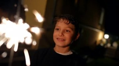 Small boy holding sparkler celebrating holidays