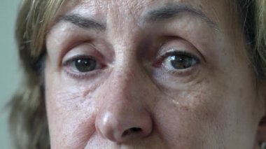Mature woman eyes looking at camera with concerned expression. Macro female senior person eye