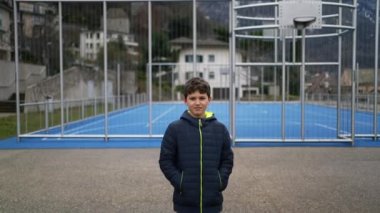 Ciddi bir ifadeyle şehir parkının dışında duran düşünceli genç bir çocuk. Kışlık giysiler giyen düşünceli çocuk dışarıda duruyor. Portre yüzü