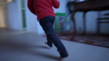 Evdeki oturma odasında koşan mutlu çocuk. Modern evdeki çocuk ayak koşucusu. El bilgisayarı görüntüleri