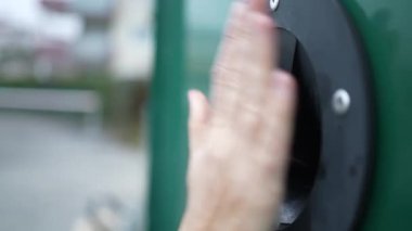 Closeup hand inserting glass bottle into dispenser. Recycling concept