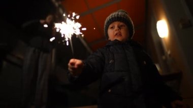 Happy small boy holding fire sparkler celebrating new year festivities in slow motion