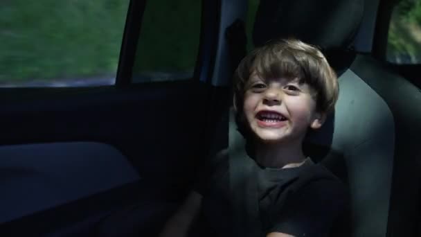 1つの幸せな小さな男の子の道路の車の後部座席に座って旅行 移動中の車内シートベルト付きの子供 — ストック動画