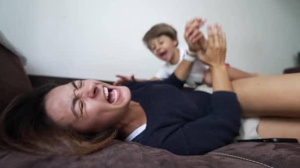 Joyful Child Jumping Mother Body Lying Sofa Indoors Kid Jumps — Vídeo de Stock
