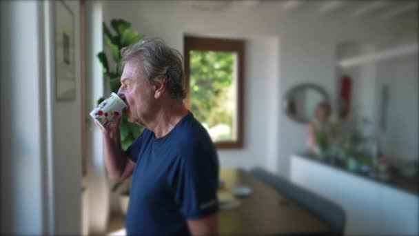 Ein Nachdenklicher Älterer Herr Steht Hause Wohnzimmer Und Trinkt Kaffee — Stockvideo
