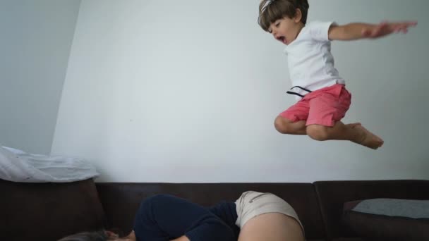Забавный Активный Ребенок Прыгает Диване Замедленной Съемке Поверх Мамы Счастливый — стоковое видео