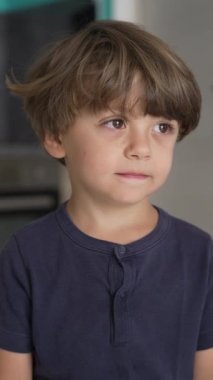 Düşünceli bir çocuğun portresi. Dikey Videodaki küçük bir çocuğun düşünceli ifadesi.