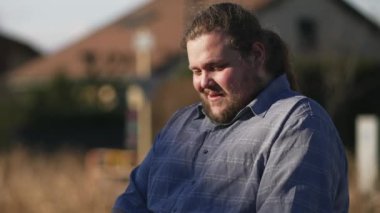 Happy young man using laptop sitting outdoors in city with casual clothing. One freelancer working remotely in front of computer in sunlight