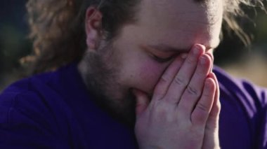 Dua eden adam Tanrı 'dan yardım istiyor. Yüzü kapalı, elleri sımsıkı kapalı meditasyonda dua ederken. Umut ve İnanç kavramı. İzleme görüntüsü