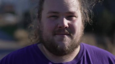 Portrait of a positive young overweight man looking at camera in tracking shot. A joyful fat guy close up face