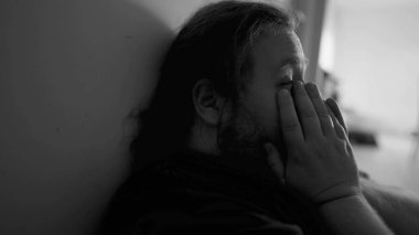 One overweight man suffering from depression at home corridor in emotional pain in monochromatic black and white