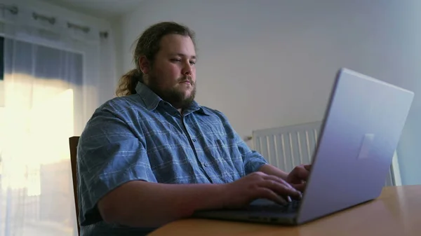 One chubby man in front of laptop working from home. Person browsing internet using computer liking content online celebrating success