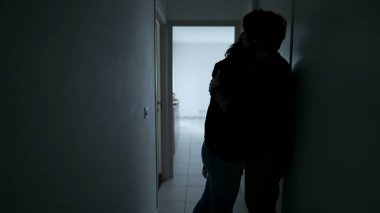 Silhouette of Man embracing woman standing in home corridor. Young Couple going through hard times. Husband and wife hugging during depression. Support and counseling concept