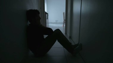 Depressed man sitting on floor. Sad unhappy person holding his forehead suffering from mental illness. Depression concept