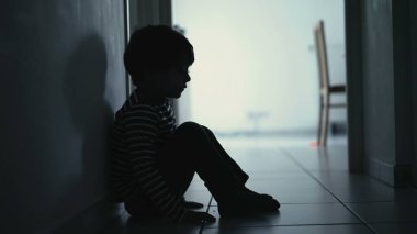 Depresyondan muzdarip üzgün bir çocuk koridorda tek başına oturmuş yalnızlık hissediyor. Evde yüzü siluetle kaplı korkmuş, küçük bir çocuk.