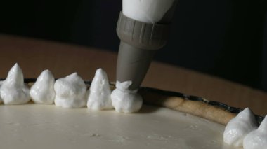Pastry pag adding cream on top of cake decoration