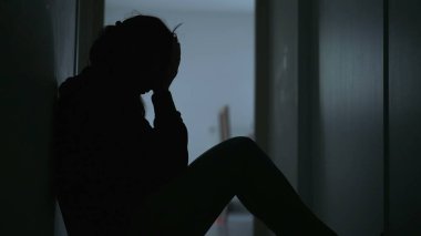 Lonely woman sitting at home alone on floor covering face in shame and regret. Person suffering from trauma feelng anxiety and depression