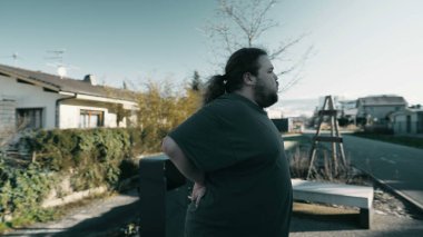 Dramatic moment of person suffering from back pain. An overweight man having physical injury outside