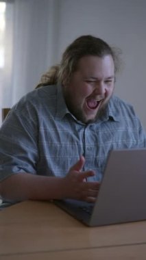 Happy man in front of computer receiving excellent news dancing in celebration. Excited male entrepreneur looking at laptop feeling excitement. vertical video