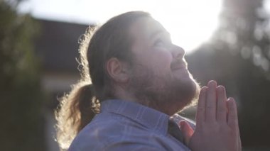 One religious overweight young man in prayer outdoors closing eyes in contemplation