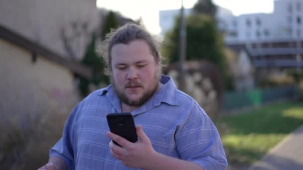 Young Man Receiving Negative News Cellphone Device While Walking Outdoors — Vídeos de Stock