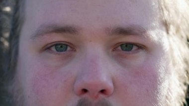 Young man with blue eyes close up macro face looking at camera. One chubby caucasian male person with neutral expression