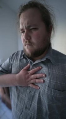 Unwell young man having chest pains unable to breath. One fat overweight sedentary male person suffering heart pulpitations. Unhealthy lifestyle concept in vertical video