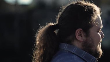 Happy person walking outdoors. Contemplative expression of a young overweight man walks outside in slow motion tracking shot profile close up face