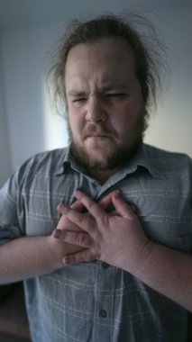 Unwell young man having chest pains unable to breath. One fat overweight sedentary male person suffering heart pulpitations. Unhealthy lifestyle concept in vertical video