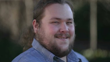 Person working in front of laptop in city park outdoors with casual clothes. Freelancer or student browsing internet in remote work